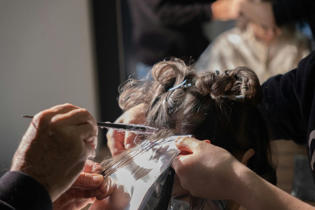 Hairdresser applying foil highlights to client's hair in a salon.